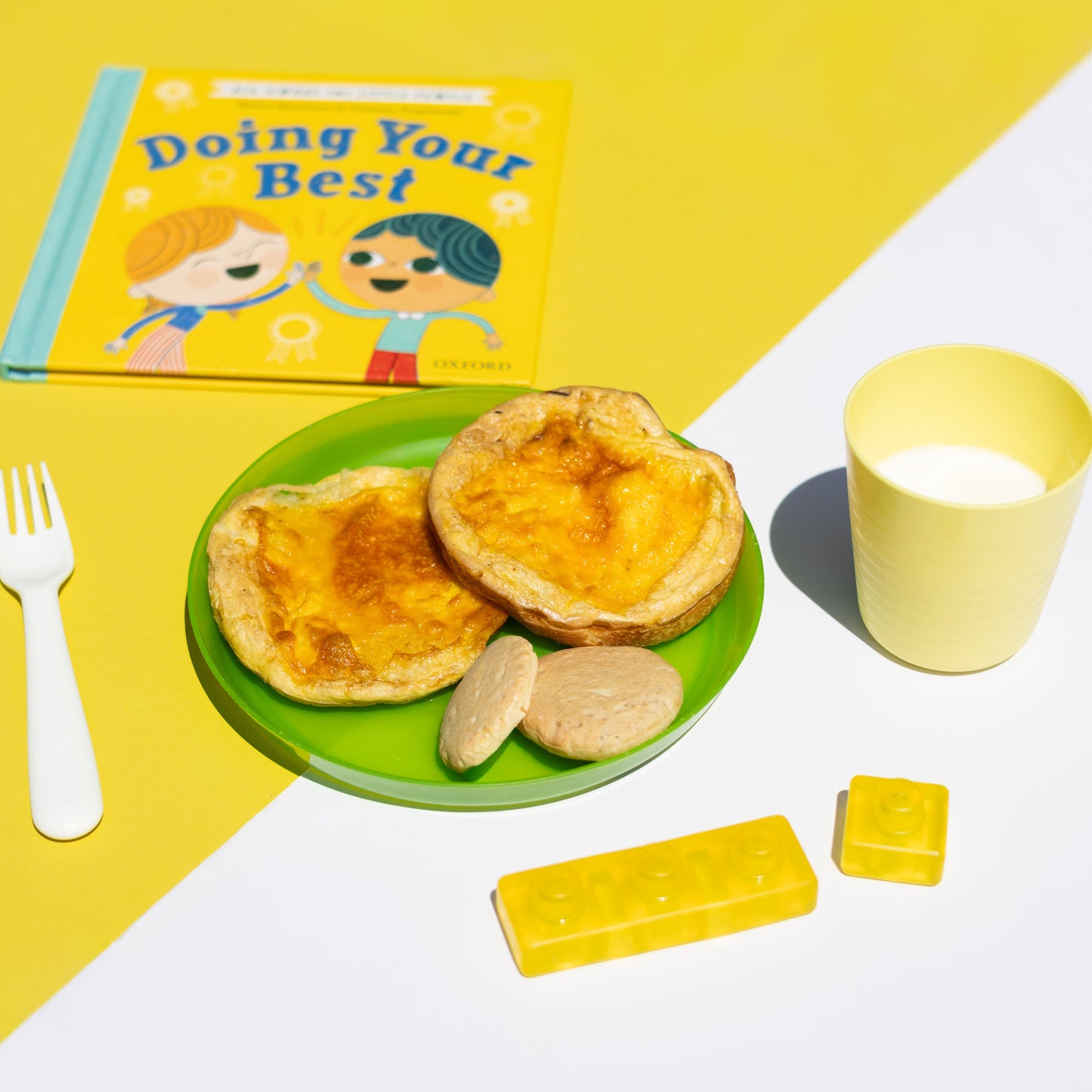 Children's book titled 'Doing Your Best' with a plate of food, cup, and toys on a yellow and white background.